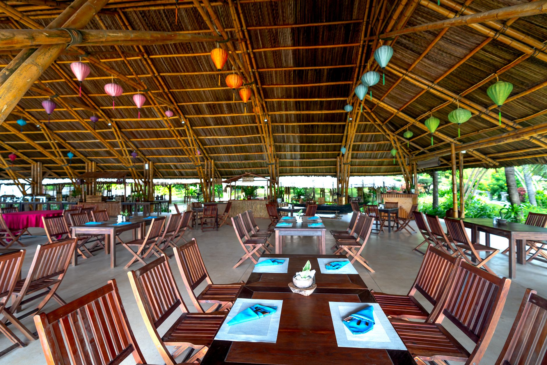 Open-sided resort restaurant with timber tables set under a high roof