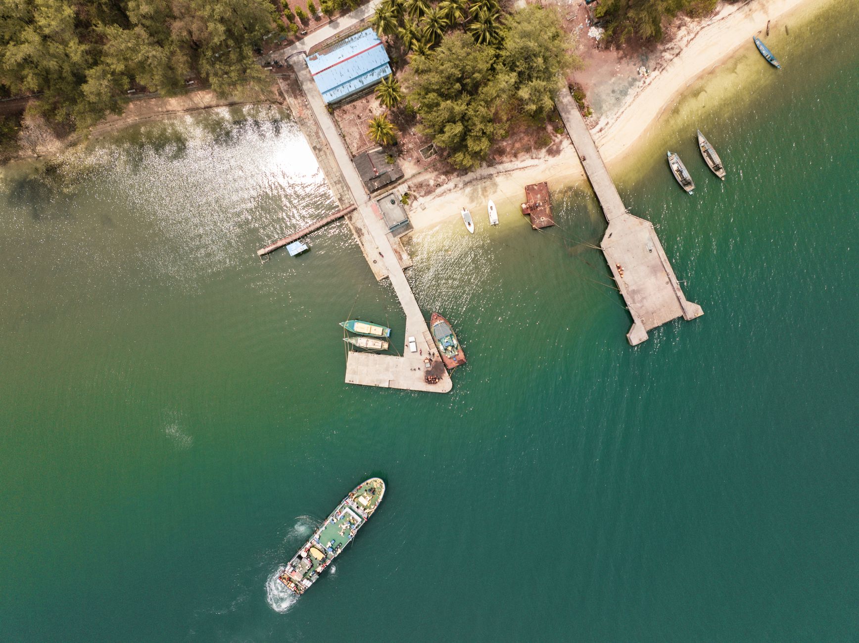 Aerial view of a timber jetty reaching into a turquoise bay