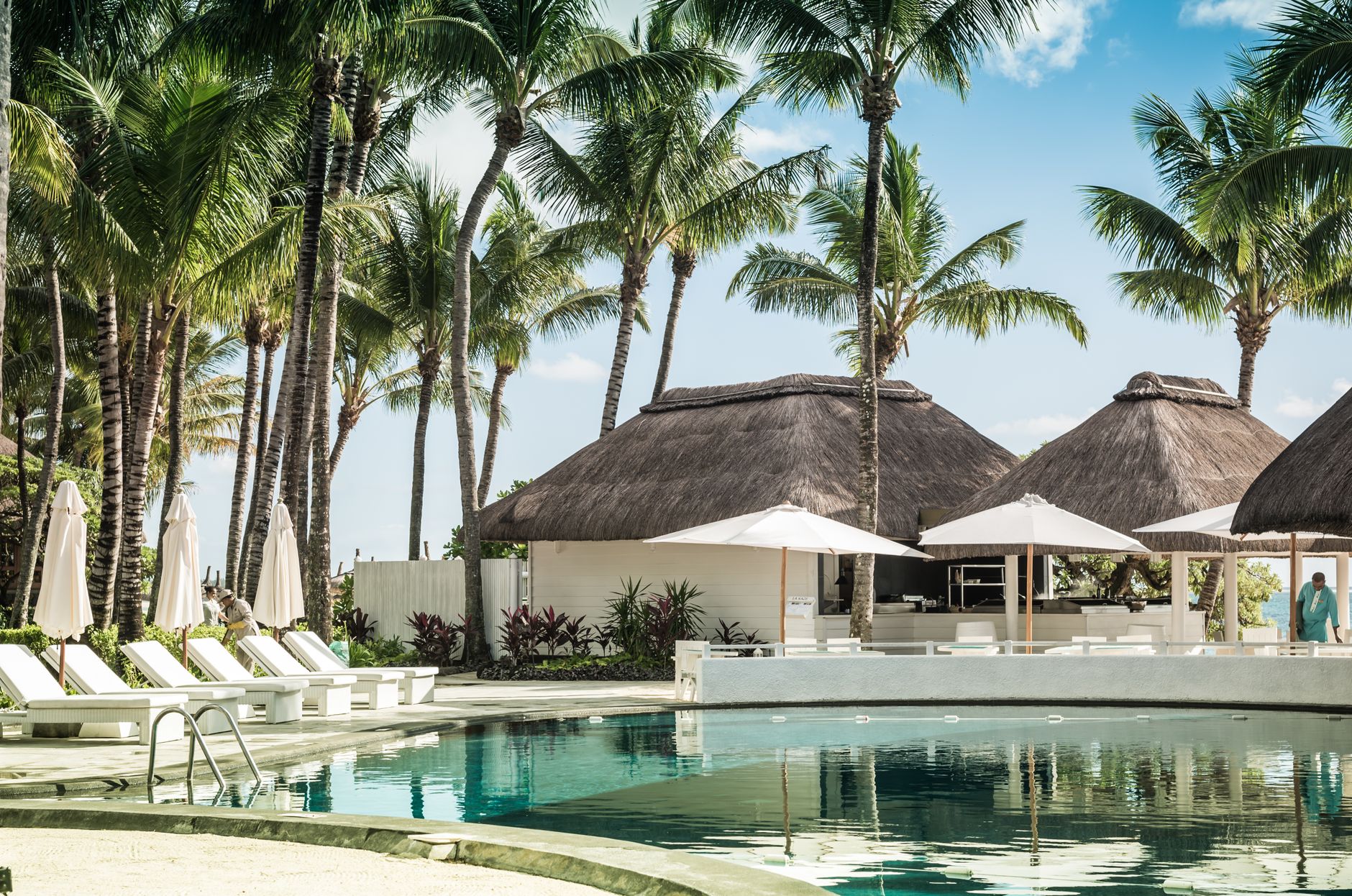 Resort pool ringed by palms and sun loungers